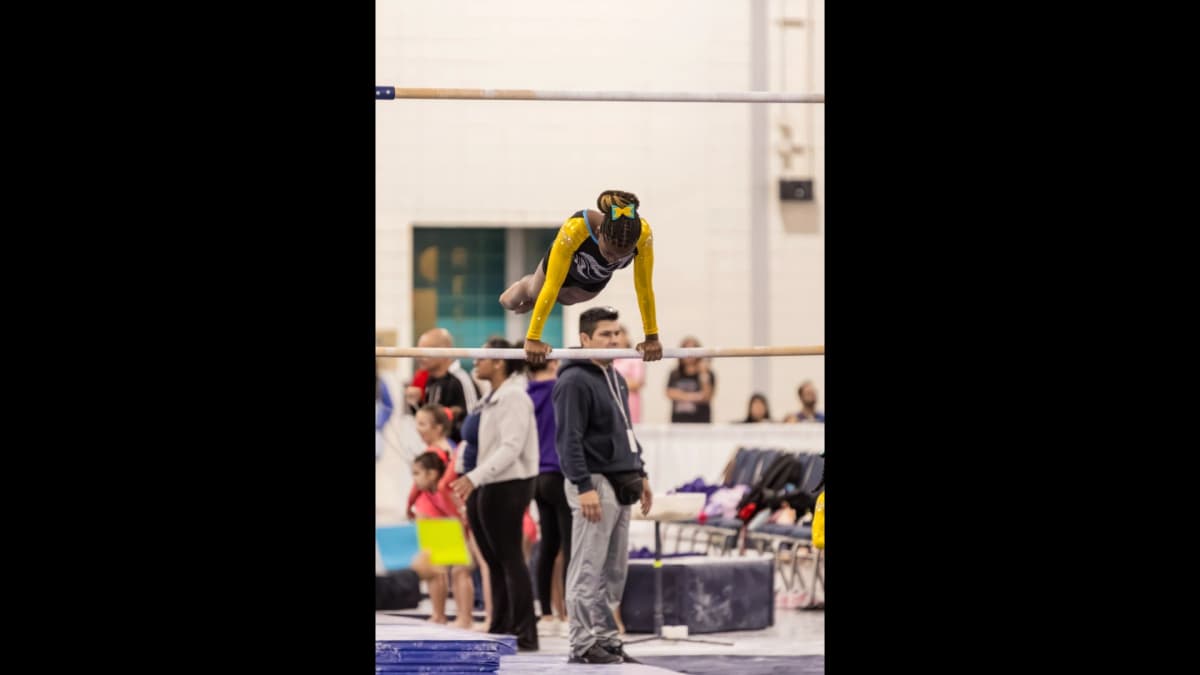 Gymnast performing on uneven bars during competition
